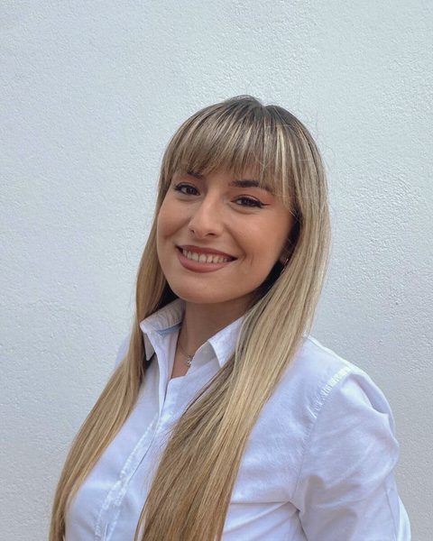 Áurea Fernández, con camisa blanca, sonríe a cámara