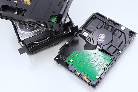 An opened hard drive next to a dismantled optical drive on a white table