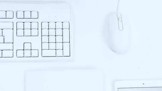 A keyboard, mouse and tablet laid out on a white desk