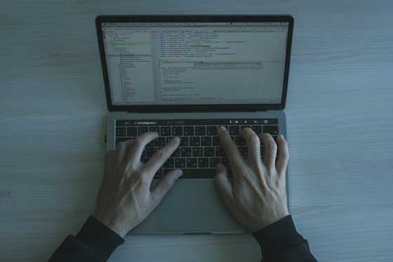 Hands typing on a laptop with a configuration console open on screen