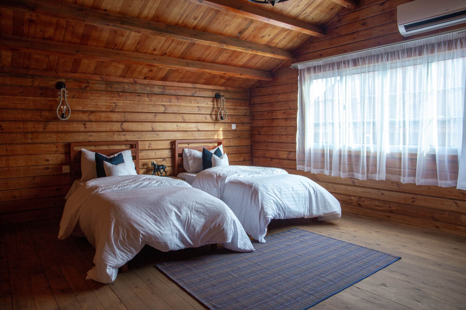 Habitación de paredes de madera con dos camas individuales y ropa blanca
