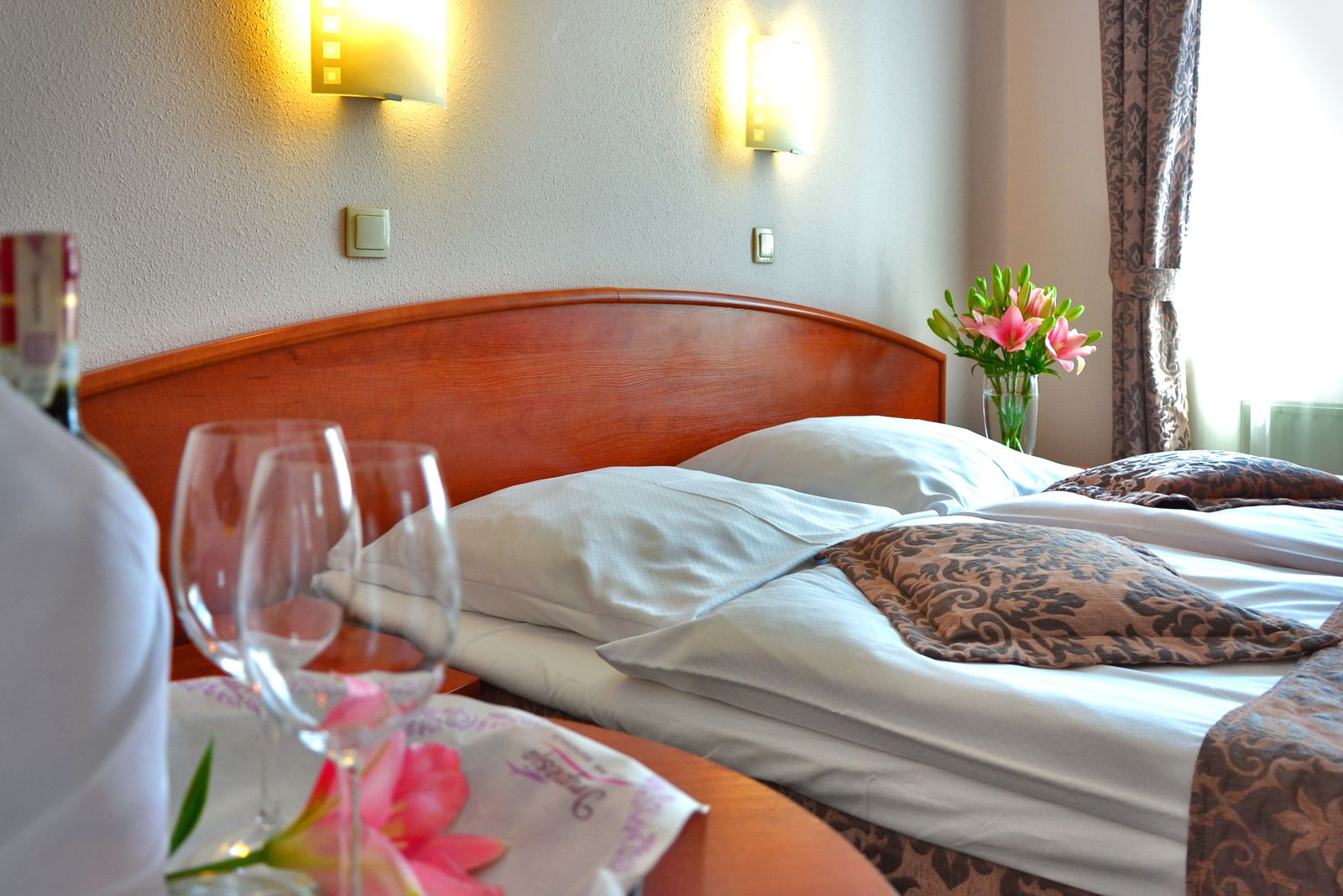 Habitación amplia con cabecero de madera, mesita y flores junto a la cama