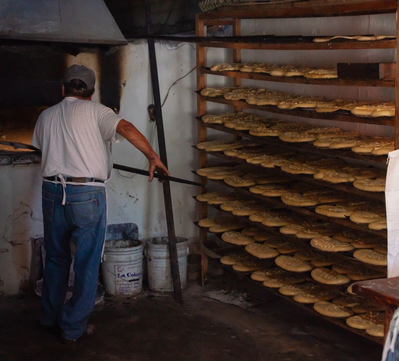 Interior de un obrador con estanterías de madera llenas de hogazas recién horneadas.